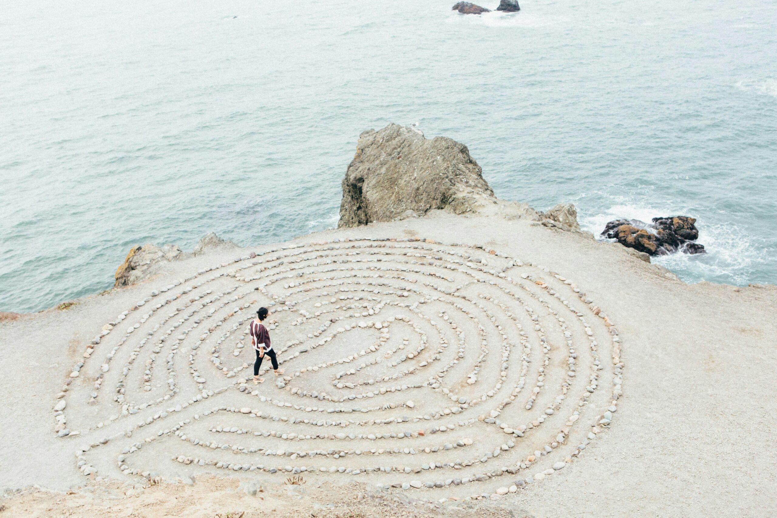 Person walks through stone maze on the cliff beside the ocean